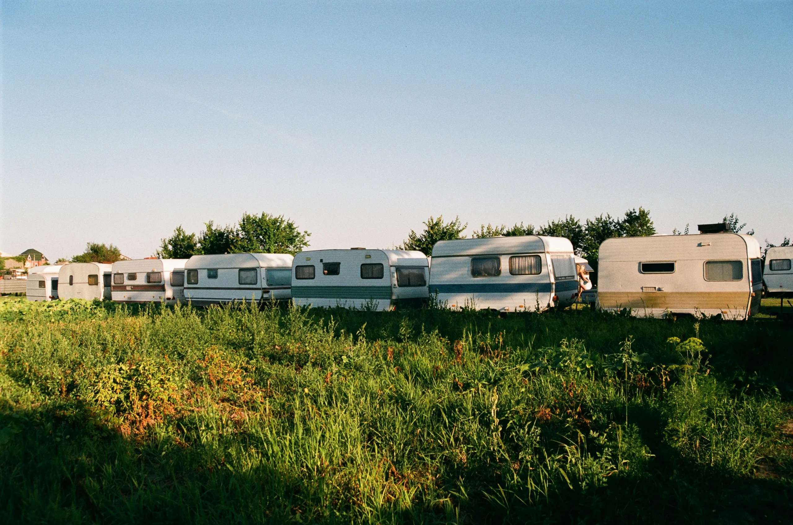Caravanas en fila sobre el césped verde entre los árboles